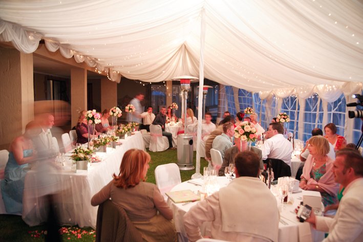 Wedding reception dinner under a white marquee with fairy lights